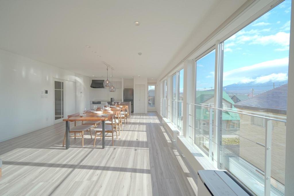 a dining room with a table and large windows at Glee Niseko LUX condo 羊蹄山一望 新築 駐車場完備 in Kutchan