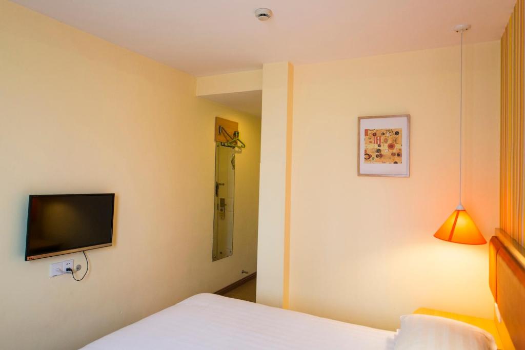 1 dormitorio con 1 cama y TV en la pared en Home Inn Guiyang Railway Station en Guiyang