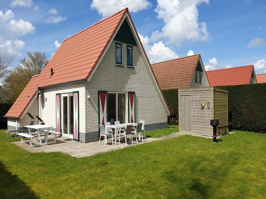 a house with a table and chairs in the yard at Modern Beach Retreat Sauna in Breskens