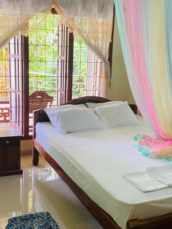a bed with a canopy in a room with windows at SiSi Place in Dickwella