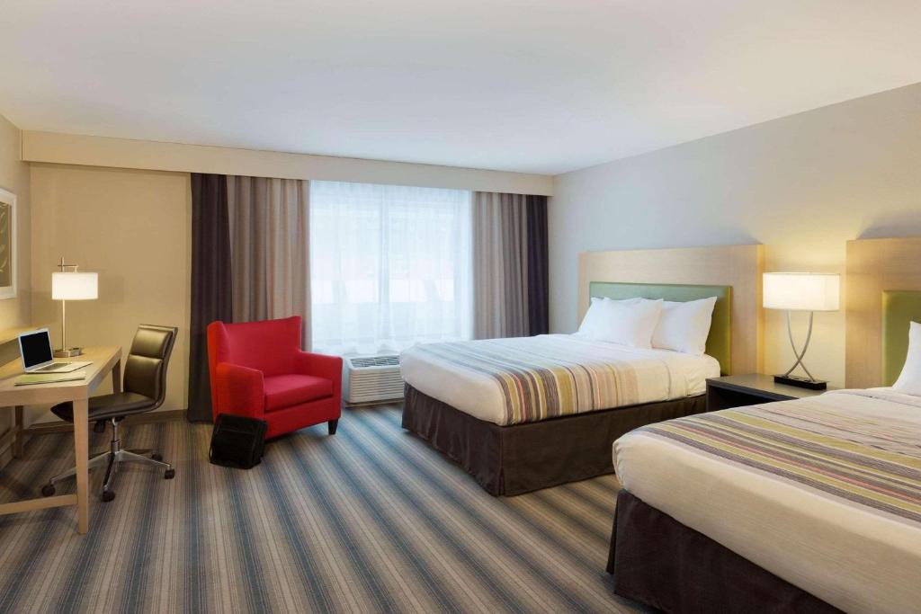 a hotel room with two beds and a red chair at Country Inn & Suites by Radisson Roseville - St Paul in Roseville