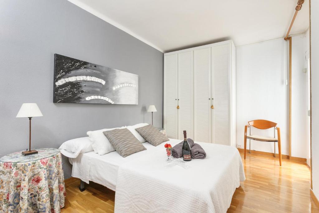 a white bedroom with two beds and a chair at Matarolux 2 in Mataró