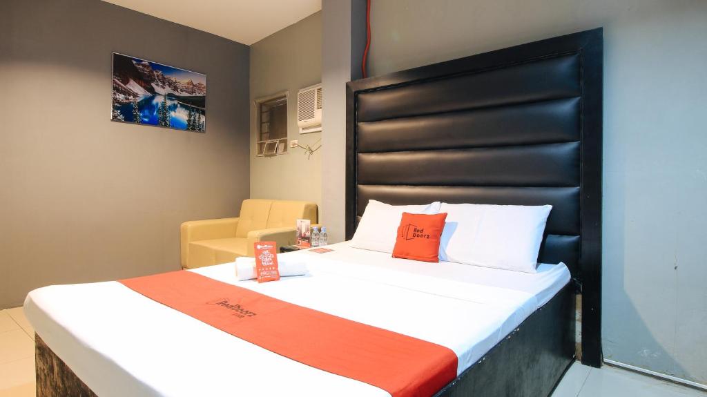 a bedroom with a large bed with white sheets and orange pillows at RedDoorz @ P Florentino Street Sampaloc Manila in Manila