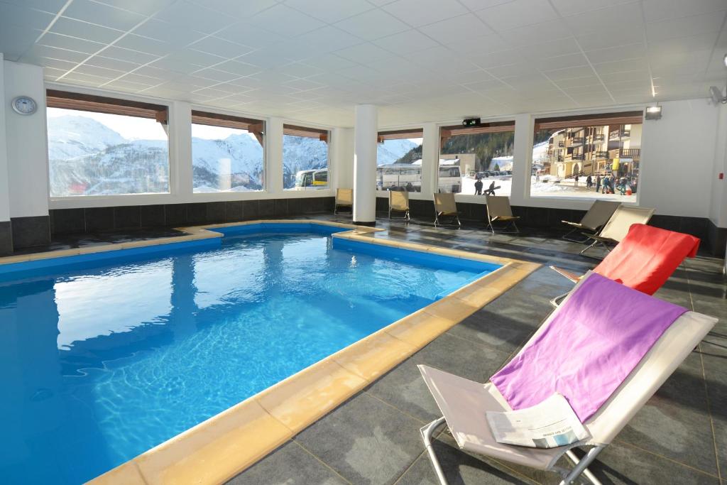una piscina in un hotel con sedie di Résidence Odalys Les Balcons d'Auréa ad Auris
