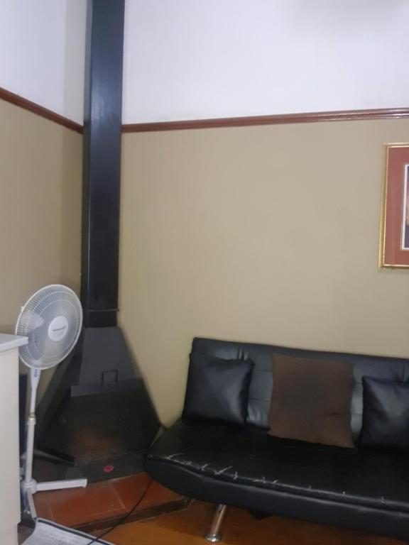 Sofá negro en una habitación con ventilador en Room Parow, Cape Town, en Cape Town
