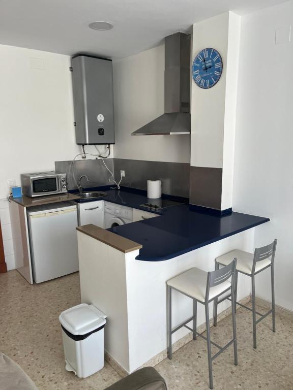 a kitchen with a counter and two chairs and a clock at San Mateo Loft in Tarifa