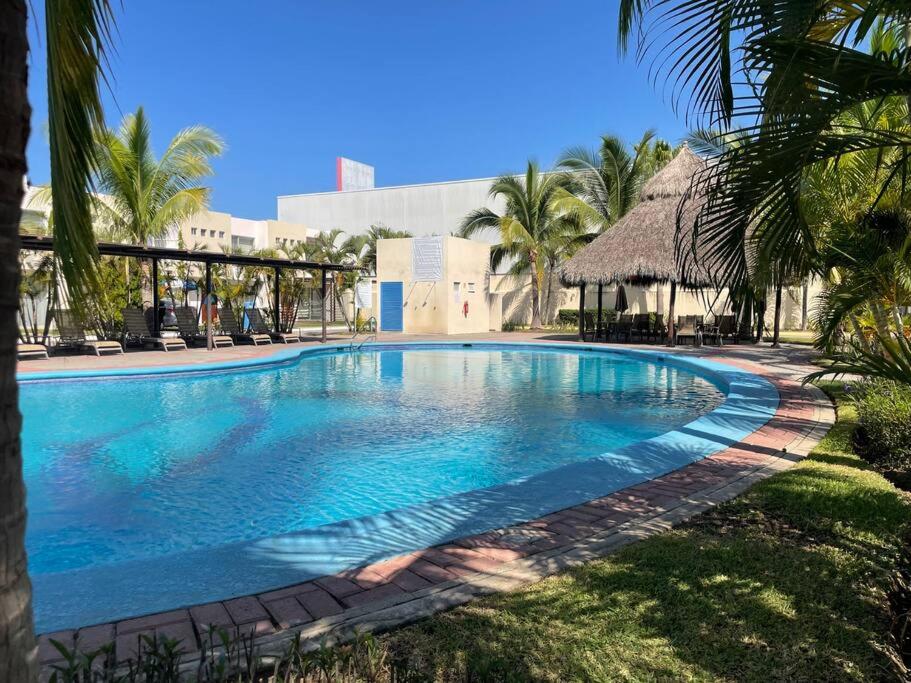 a large swimming pool in a resort with palm trees at Casa entera en fraccionamiento bahia azul in Mezcales
