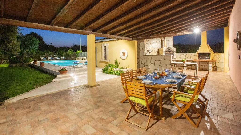 patio ze stołem i krzesłami oraz basenem w obiekcie Il Giardino Dei Limoni 8, Emma Villas w mieście Ispica