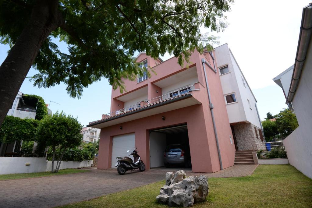 a motorcycle parked in front of a pink building at Apartments Leonarda in Murter