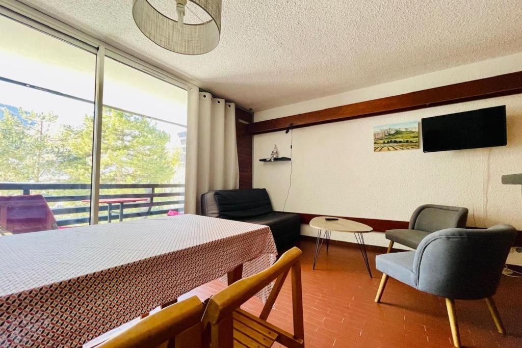 une pièce avec une table et des chaises et une grande fenêtre dans l'établissement Cosy T2 with sunny terrace in Saint-Chaffrey, à Saint-Chaffrey