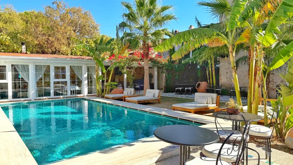 a swimming pool with tables and chairs next to a house at Jardin d'Azur Alaçatı in Alacati