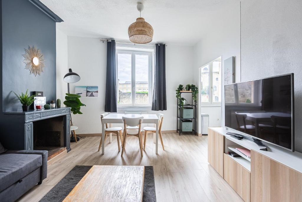 un salon avec une table, des chaises et une télévision dans l'établissement Escapade Pey Berland, à Bordeaux