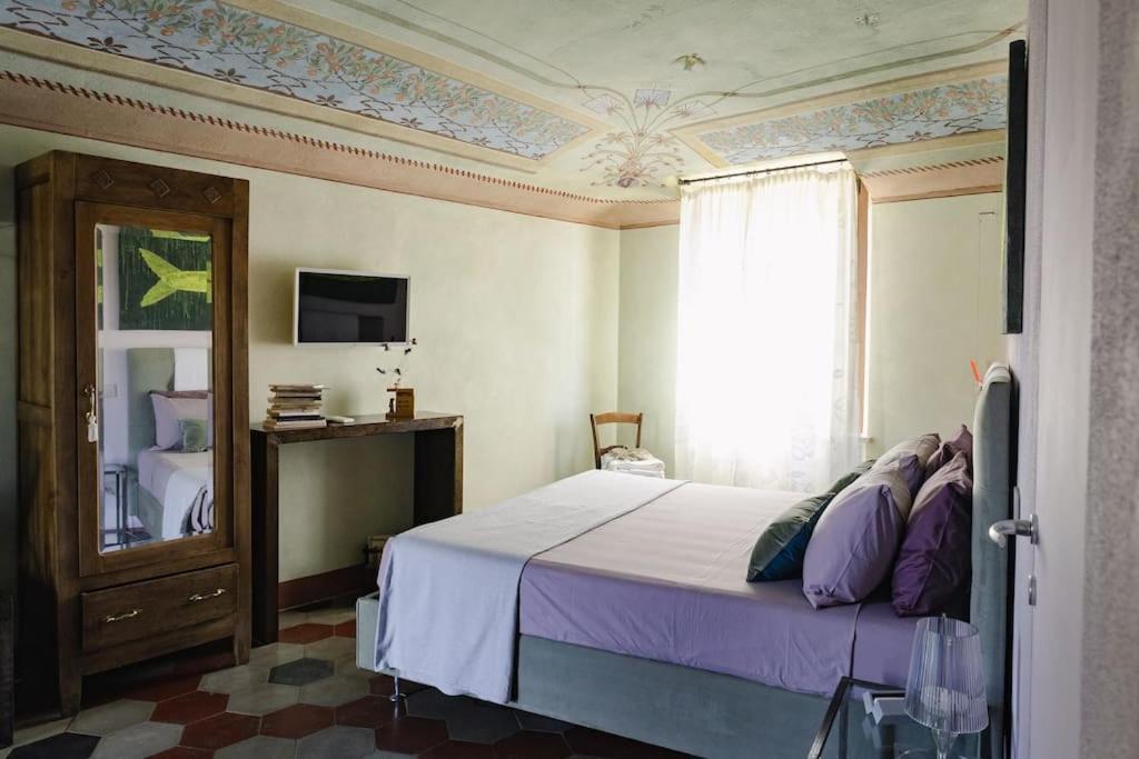 - une chambre avec un lit doté de draps violets et une fenêtre dans l'établissement Eramare - Charming Suite in the Countryside, à Asti