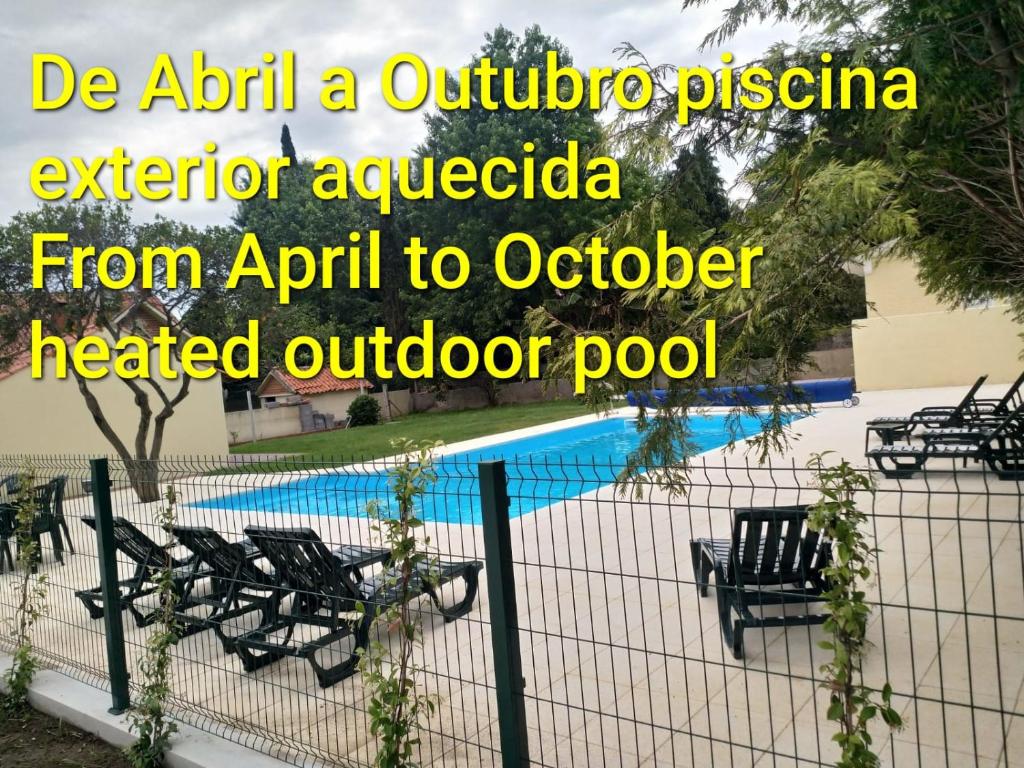 a fence with chairs next to a pool at Metro Vilar Suites & Villas in Vilar do Pinheiro