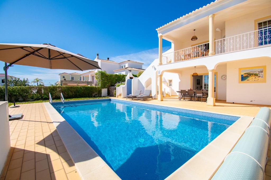 a villa with a swimming pool in front of a house at Casa Filipa Lower Floor - Charming 3-Bedroom Villa with Heated Pool in Praia do Carvoeiro