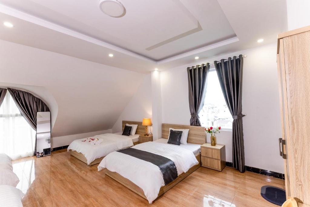 two beds in a room with two windows at Hawaii Hotel Dalat in Da Lat