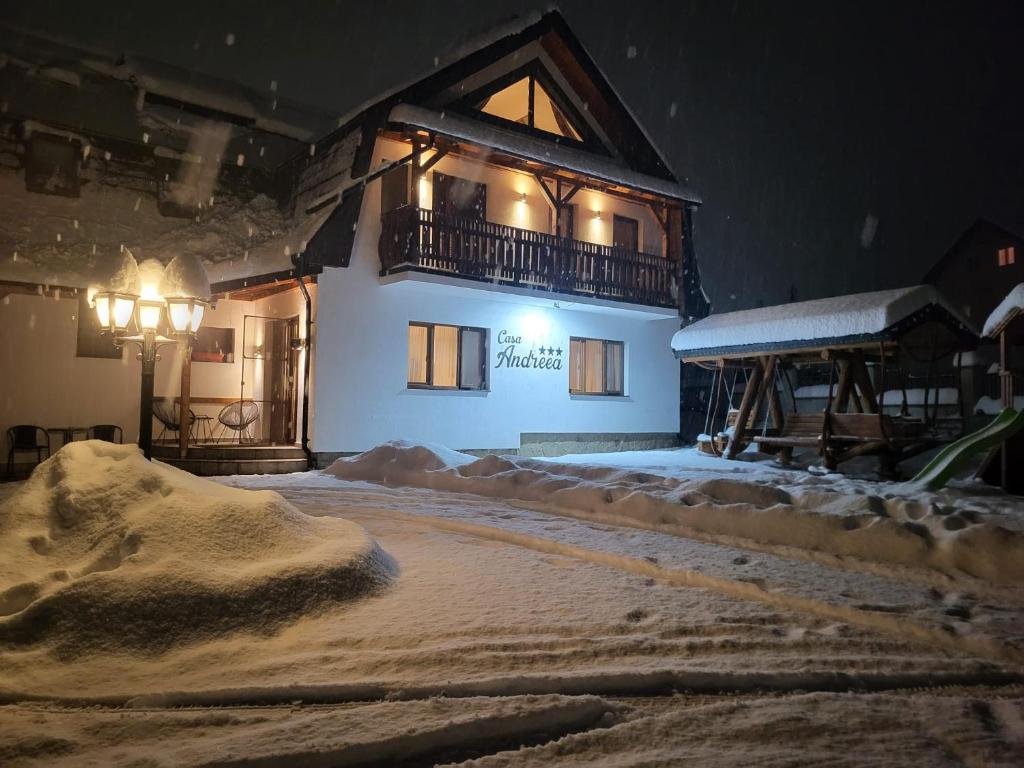 um edifício com uma varanda na neve à noite em Casa Andreea em Vatra Dornei