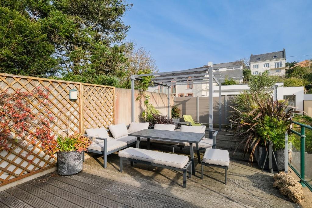 une terrasse en bois avec une table et des chaises. dans l'établissement Côté Océan - Appt vue mer de 134 m2, à Saint-Nazaire