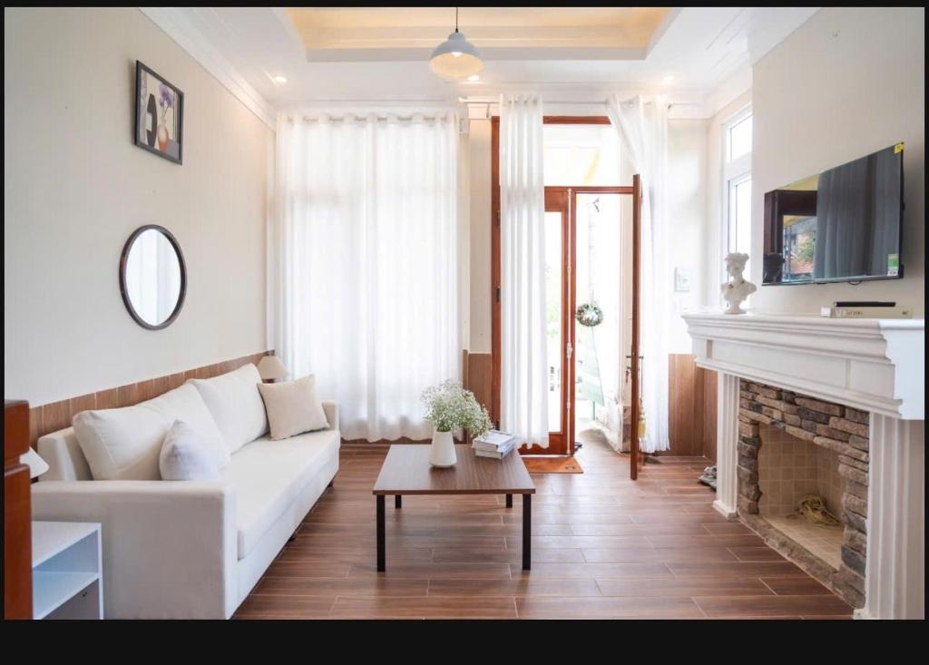 a living room with a white couch and a fireplace at 2bi s home DALAT 2 in Da Lat