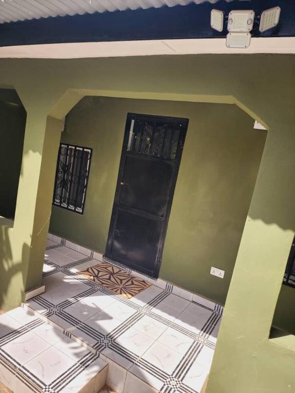 Zimmer mit schwarzer Tür und Fliesenboden in der Unterkunft Malikia apt Mo in Brusubi