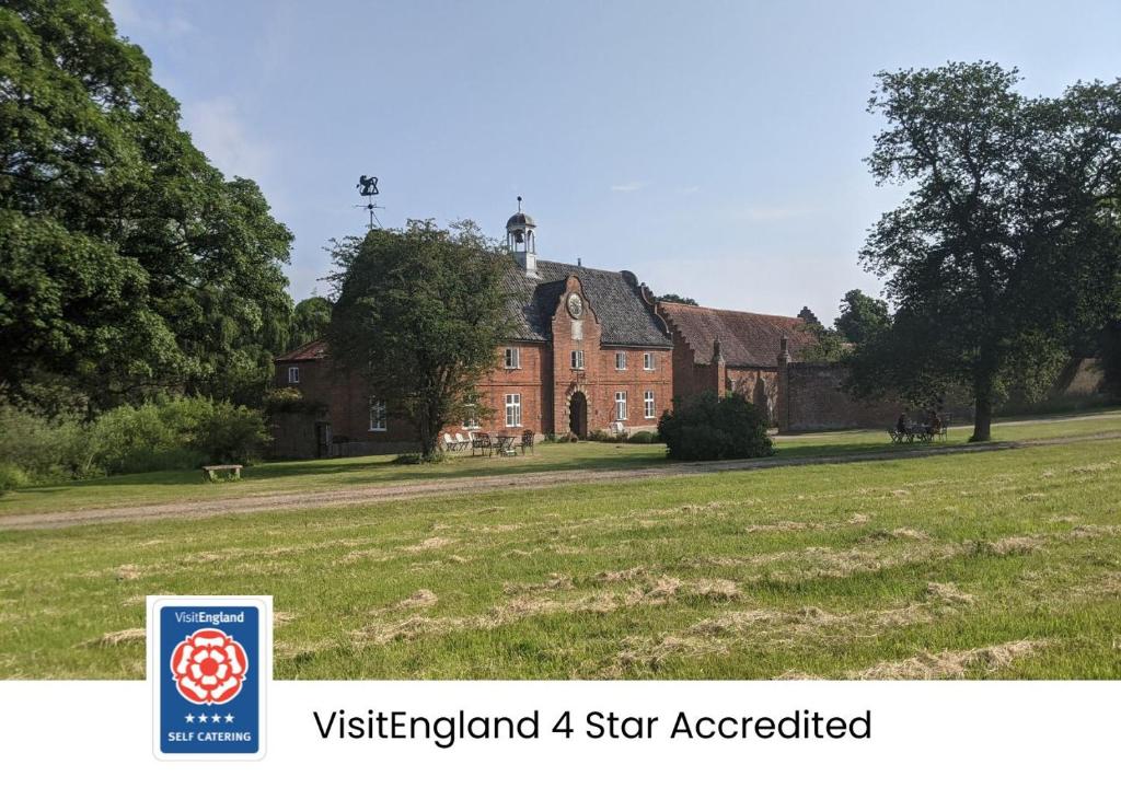 ein großes rotes Backsteinhaus mit einem Schild davor in der Unterkunft Spixworth Hall Cottages in Spixworth