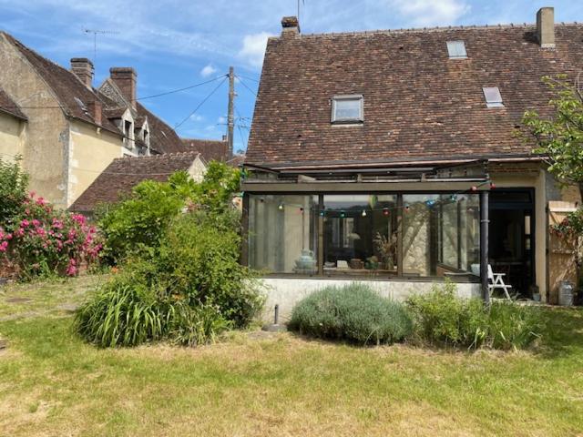 une maison avec une grande fenêtre dans une cour dans l'établissement Maison de village, à Rémalard