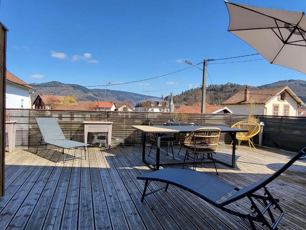 un patio avec une table, des chaises et un parasol dans l'établissement Appartement lumineux 3 chambres, terrasse, proche commerces et ski, avec WiFi - FR-1-589-677, à Le Thillot