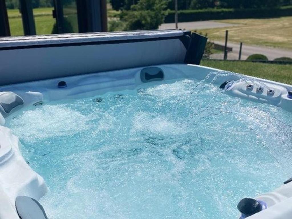 a hot tub filled with blue water in a backyard at Maison spacieuse avec spa, animaux acceptés, près d'Épinal - FR-1-589-680 in Dounoux