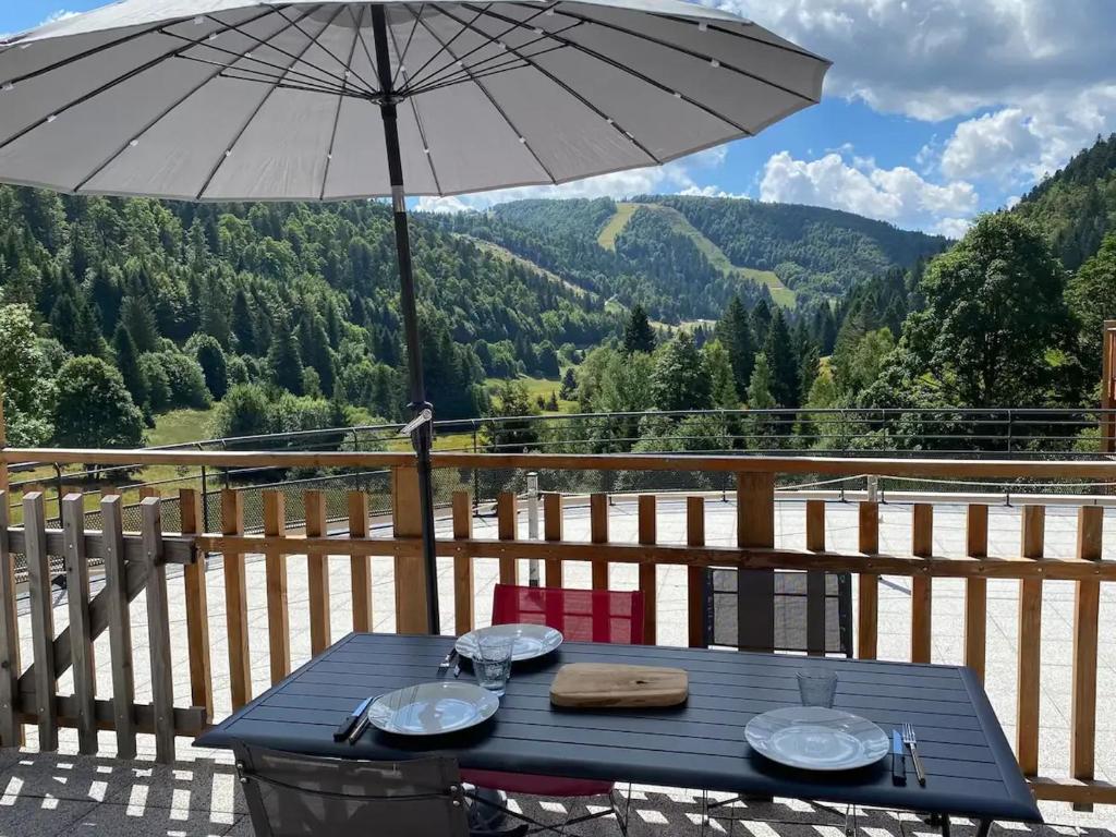 a blue picnic table with an umbrella on a balcony at Appartement moderne à La Bresse, 2 chambres, accès PMR - FR-1-589-687 in La Bresse