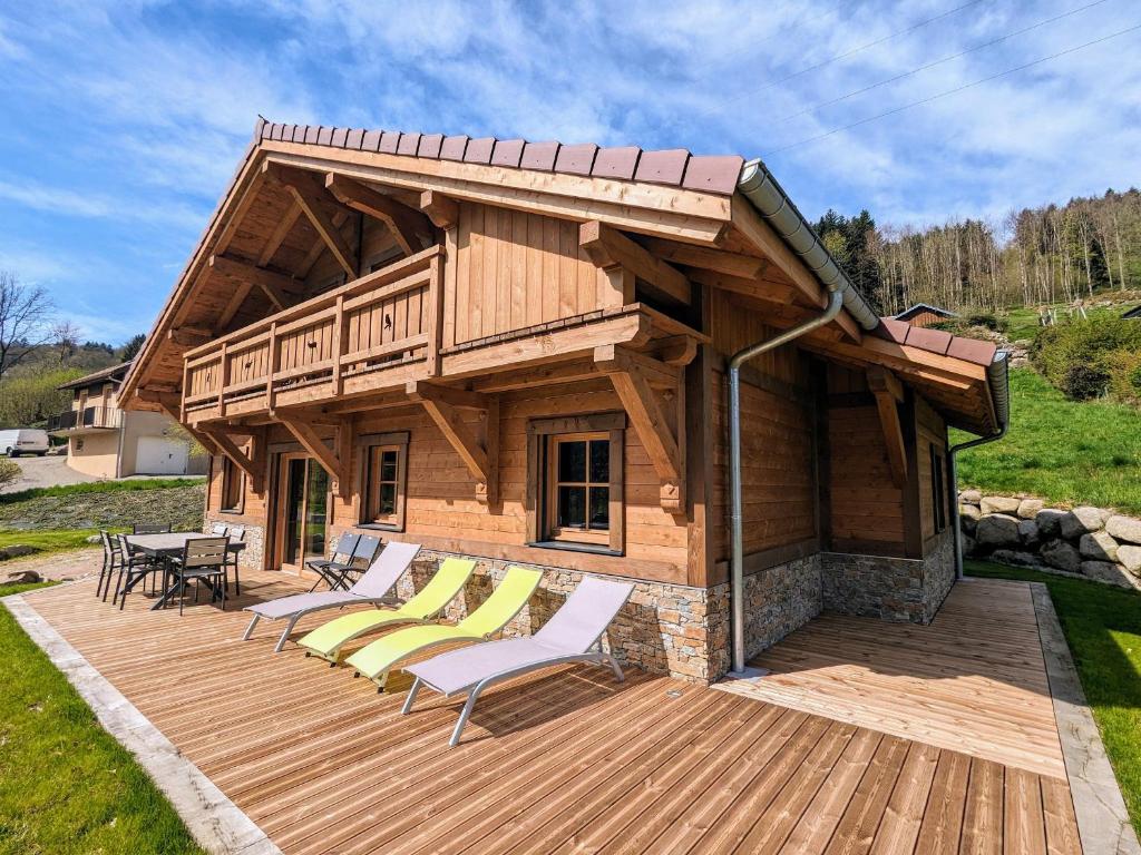 eine Holzterrasse mit Stühlen und ein Haus in der Unterkunft Chalet au cœur des Vosges avec sauna, terrasse et connexion WIFI - FR-1-589-692 in Cornimont