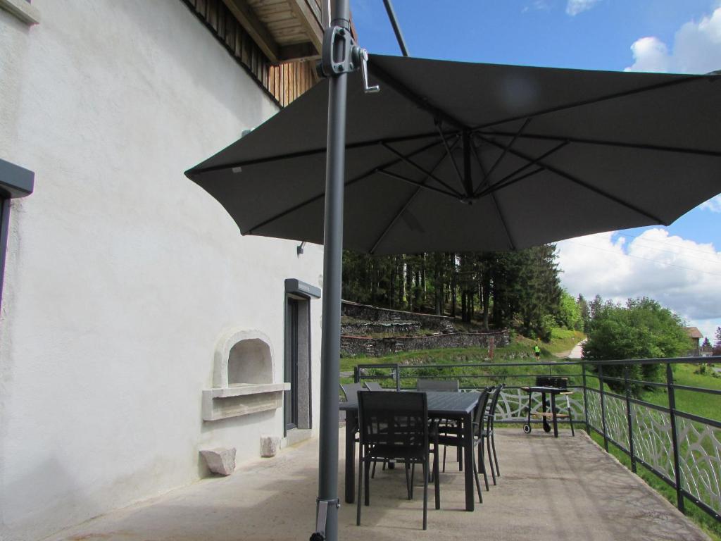 un patio avec une table, des chaises et un parasol dans l'établissement Ancienne ferme rénovée à Gérardmer, 3 chambres, confort moderne - FR-1-589-700, à Gérardmer