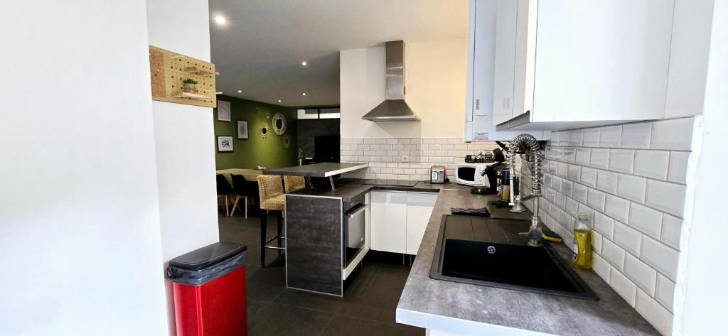 La cuisine est équipée de placards blancs et d'un évier noir. dans l'établissement Le Tandem, à Thonon-les-Bains