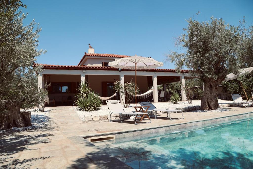a house with a swimming pool and a patio with an umbrella at Iriti's Villa & Dahlia Studio in Platanidia