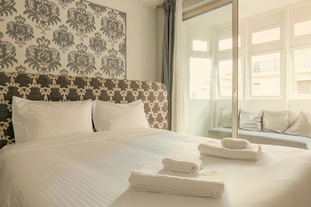 a bedroom with a white bed with two towels on it at Sliema Central Iprime Studios in Sliema