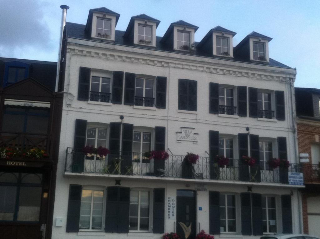 - un bâtiment blanc avec des fenêtres et des balcons à volets noirs dans l'établissement Villa des Sarcelles, au Crotoy