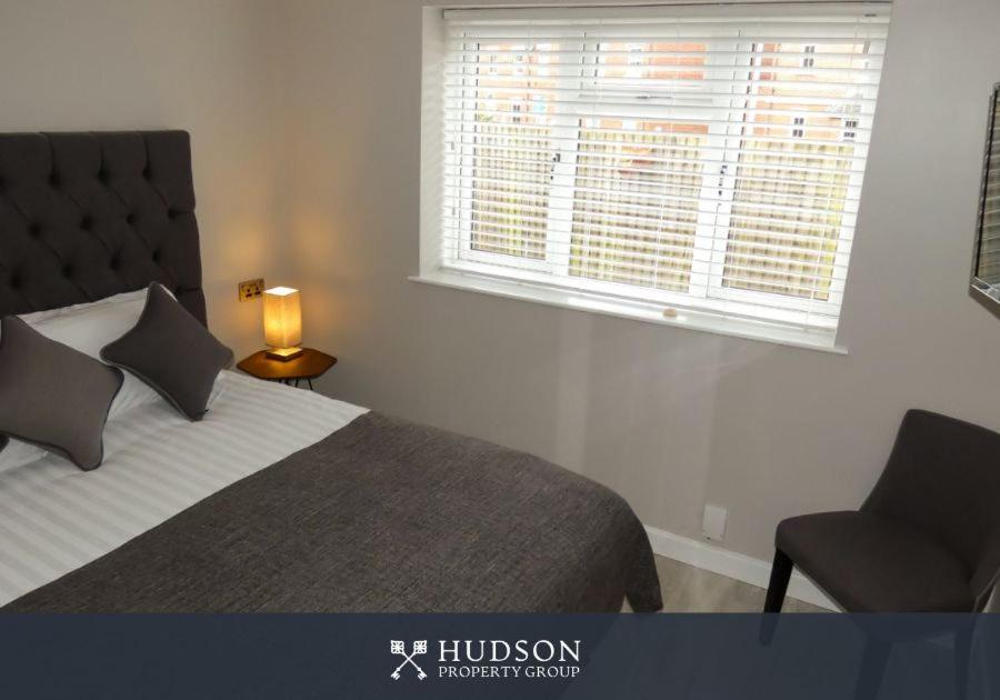 Un dormitorio con una cama y una silla y una ventana. en Serviced Apartment with Parking, en Telford