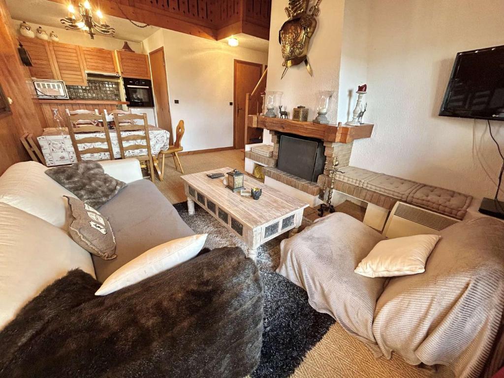 un salon avec deux canapés et une cheminée dans l'établissement Appartement cosy à Megève: 3 pièces + mezzanine, 4 couchages - Proche remontées mécaniques et golf - FR-1-597-19, à Megève