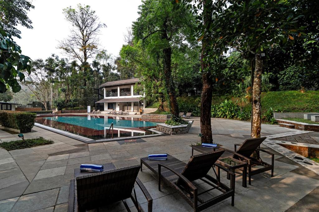 a house with a swimming pool and some chairs at Sterling Wayanad in Sultan Bathery
