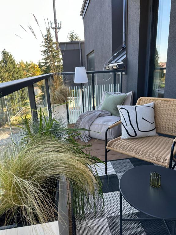 a patio with two couches and tables on a balcony at PRESTIGE ZEN Apartment & SPA by Posesja Apartamenty in Grzybowo