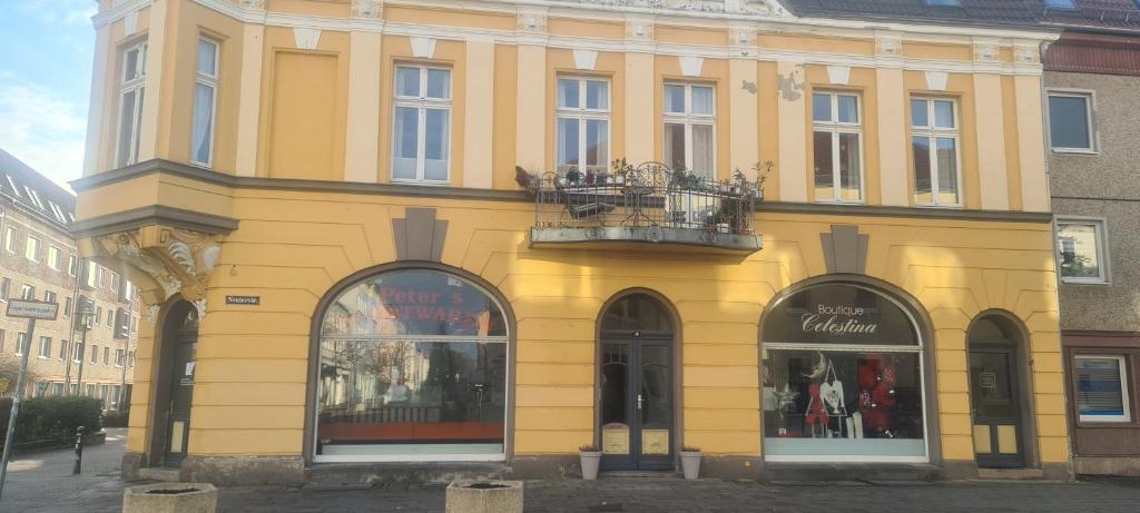 a yellow building with a balcony on a street at City Villé Ferienwohnung Innenstadt in Neubrandenburg