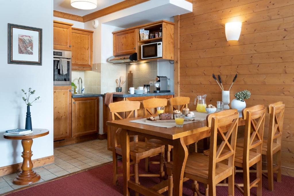 a kitchen and dining room with a wooden table and chairs at Résidence Pierre & Vacances Premium Arc 1950 Le Village in Arc 1950