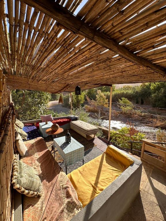 un patio con pérgola de madera y sofá en Dar Relax Hostel, Gorges de Todra, en Tinerhir