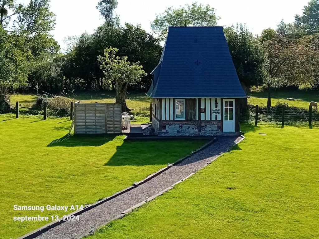een klein huis met een blauw dak in een veld bij Paisible Cahute in La Poterie-Mathieu