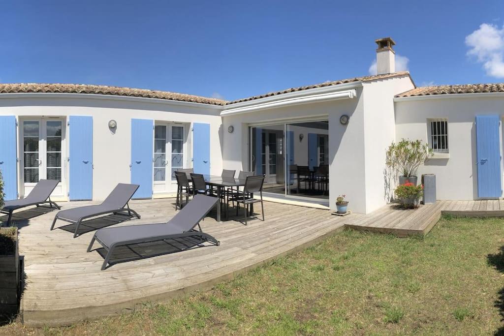 un patio avec des chaises et des tables sur une terrasse en bois dans l'établissement Maison oléronaise 8 pers proche plage et commerces, à Grand-Village-Plage