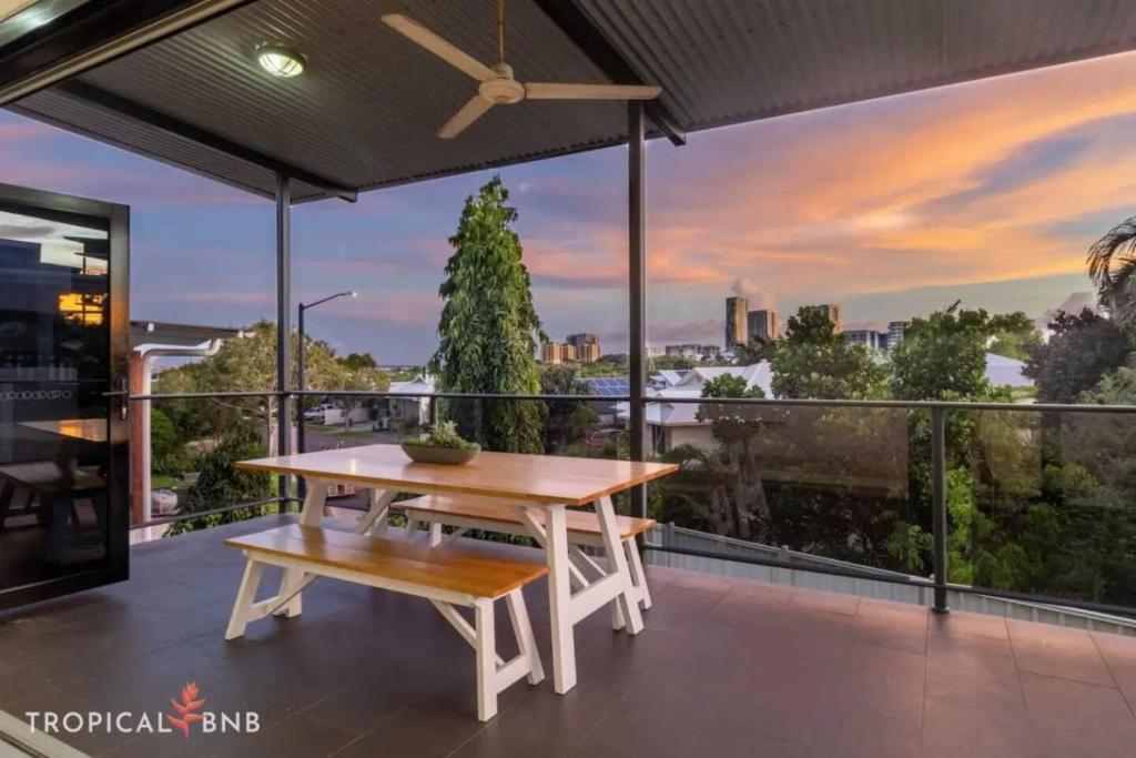 un patio con mesa y banco en un balcón en Sunsets & City Skyline Views With Pool, en Stuart Park