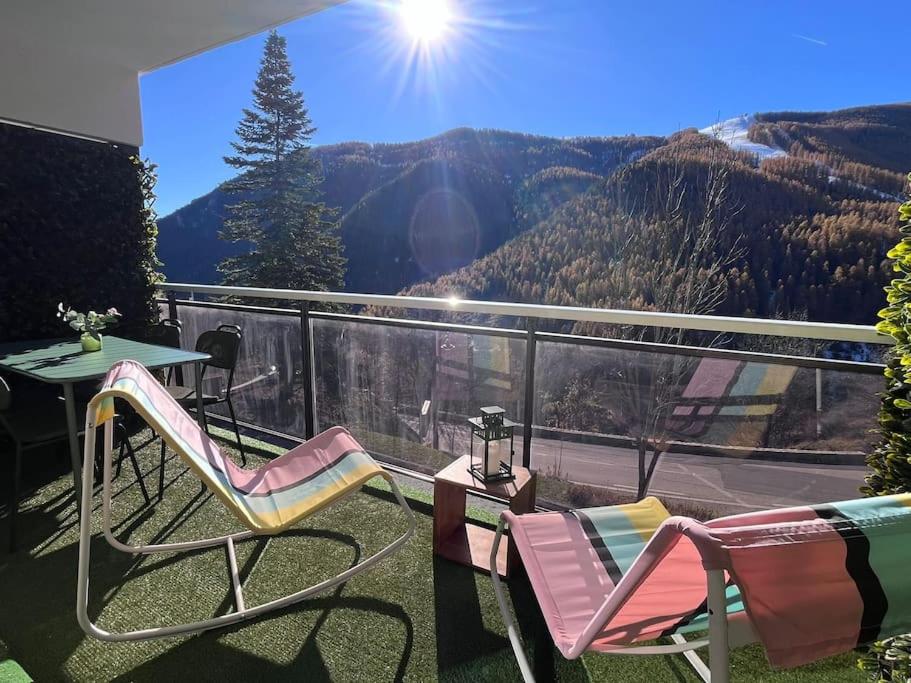 a balcony with two chairs and a table and a view at Magnifique logement plein centre face aux pistes in Auron