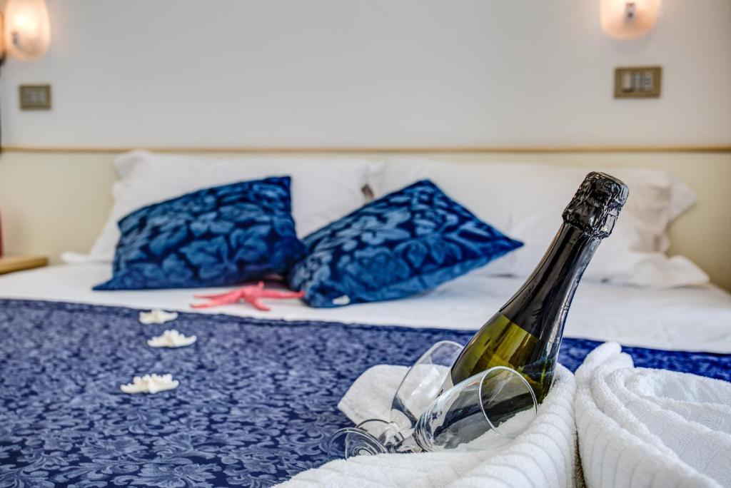 una bottiglia di vino seduta sopra un letto di Hotel Tiziana a Rimini