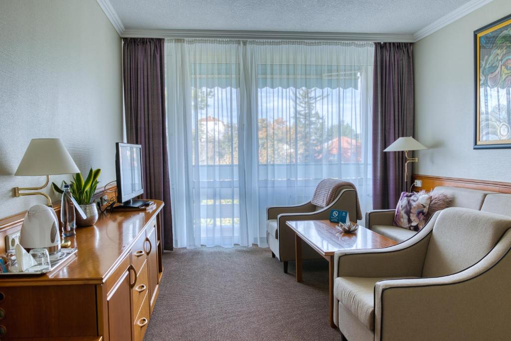 a hotel room with a couch and a table and a window at Ensana Thermal Hévíz in Hévíz