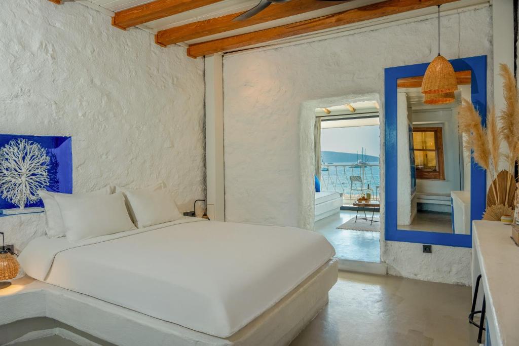 a white bedroom with a bed and a balcony at Churchill Townhouse in Bodrum City