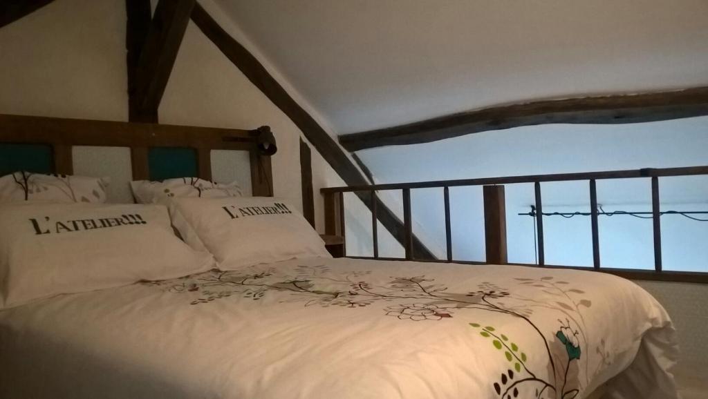 a bedroom with a bed with white blankets and pillows at La Maréchalerie L'ATELIER in Lion-en-Sullias